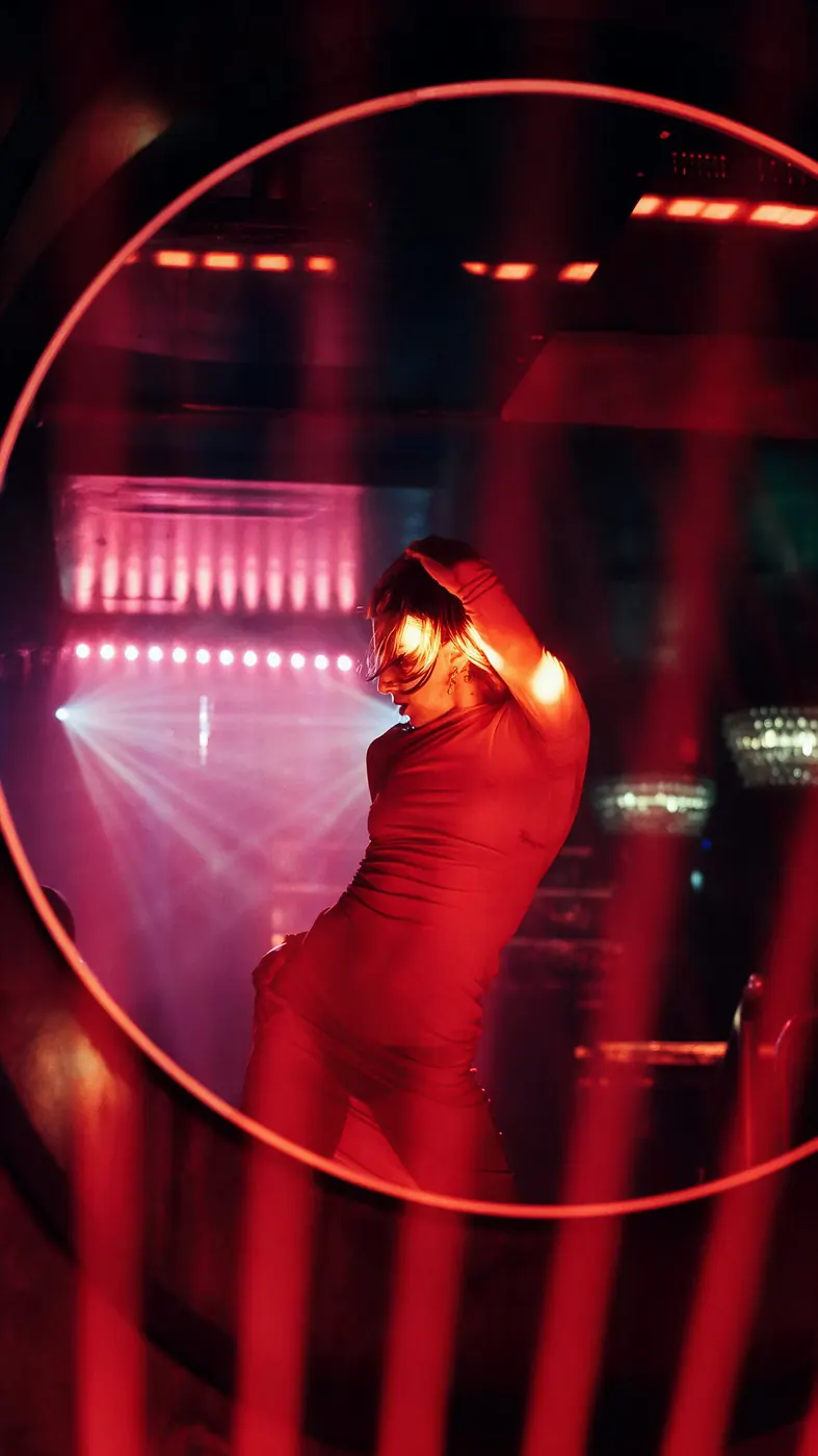 A performer in red on stage under a ring of light